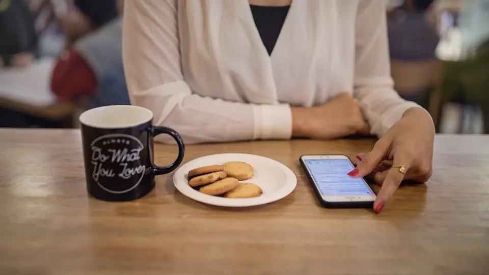 Første date: en kop kaffe og småkager på bordet ved siden af en telefon