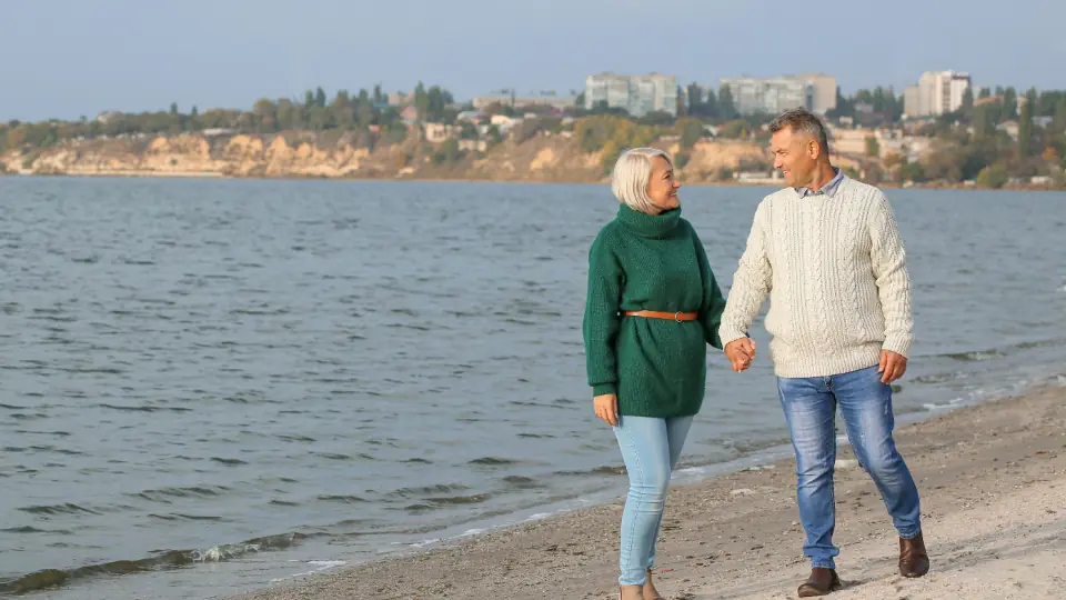 Dating sider efter 50: et ældre par går langs vandet på en strand